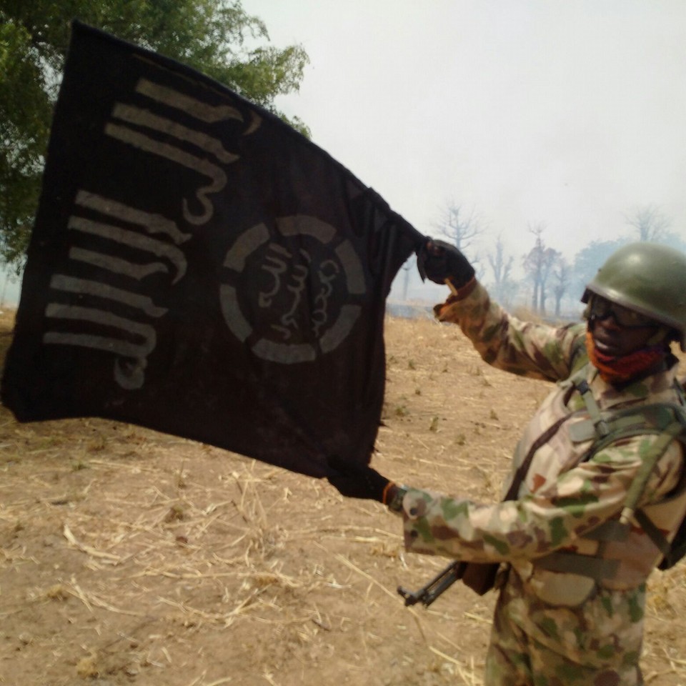 Nigerian soldier holding the Boko Haram flag after the destruction of the spiritual base