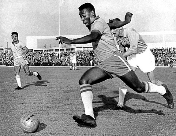 Pelé dribbling past a defender while playing for Brazil, May 1960.