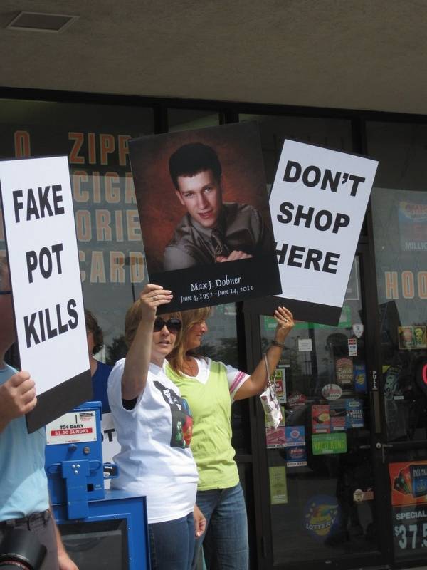 Protesters against the selling of Iaroma hold billboards of Max dobner who died to the drug