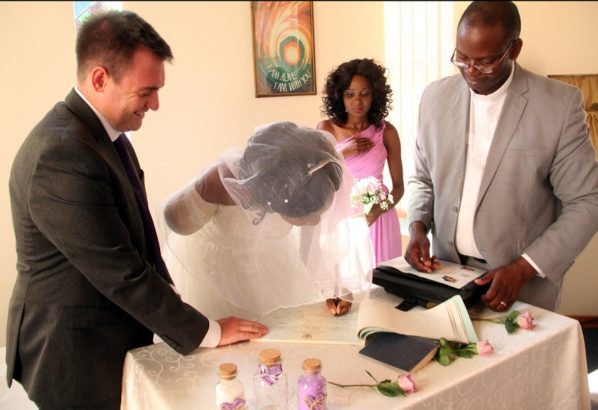 The bride Zanele Ndlovu signs a marriage certificate while the groom Jimmy Fox (left) and a pastor witness during a wedding held at a local hospital in Bulawayo yesterday